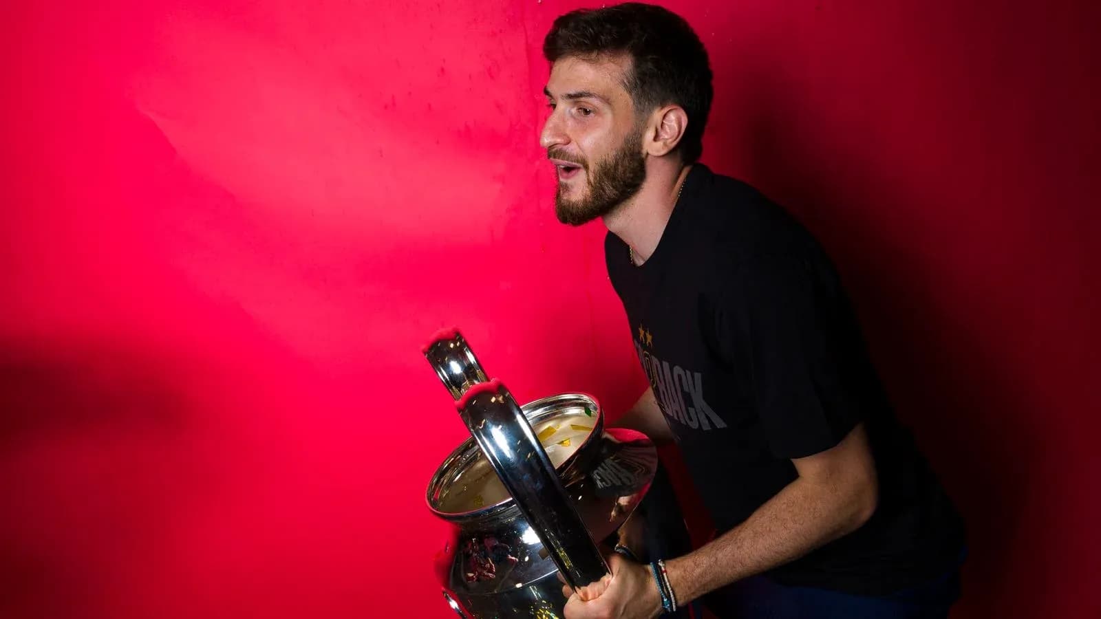 Player holding a trophy against a pink background