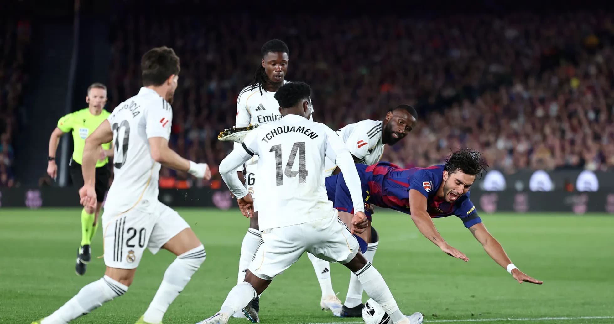 Barcelona player falling as Real Madrid defenders approach