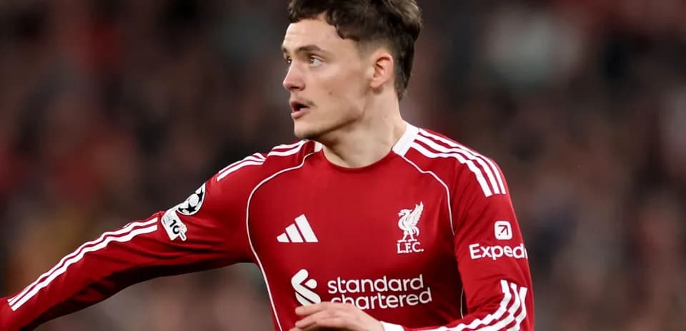 Futbolçu Liverpool formasında topa doğru hərəkət edir