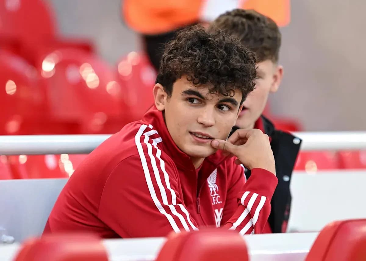 Gənc futbolçu qırmızı kostyumda oturur