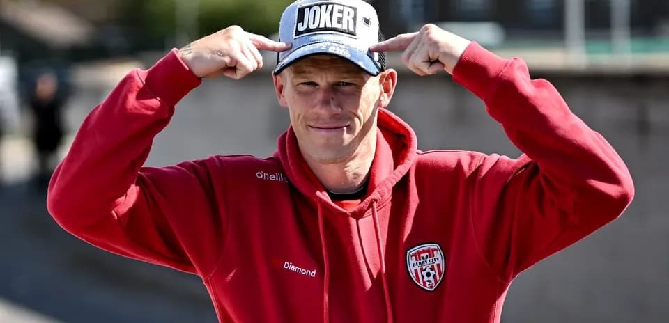 Person wearing 'JOKER' cap and red hoodie