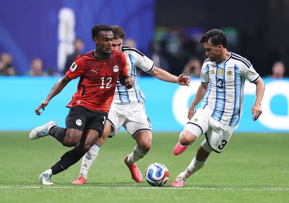 Egyptian player dribbling past two Argentine defenders