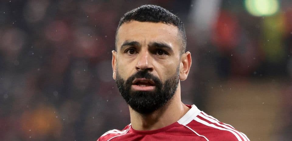 Futbolçu qırmızı forma ilə kameraya baxır