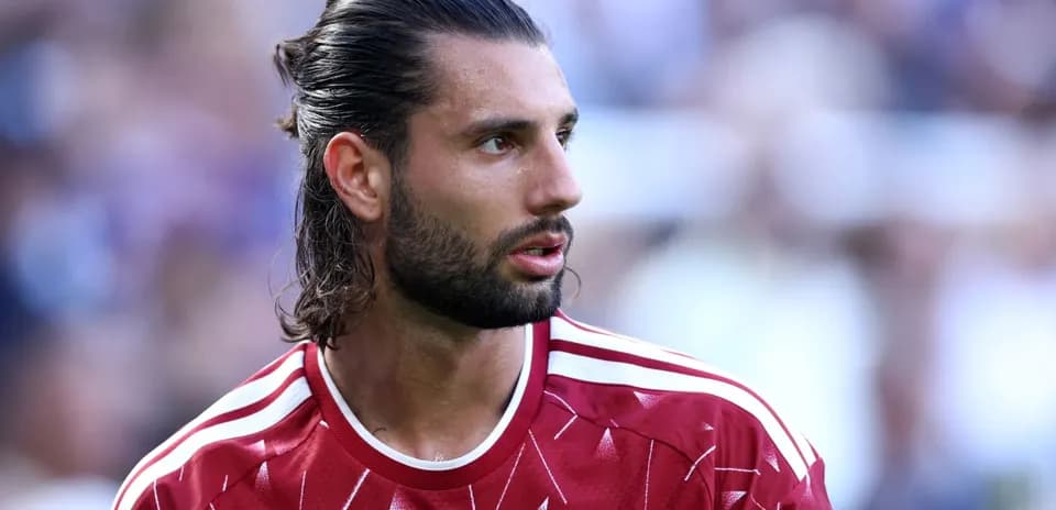 Futbolçu, qırmızı forma ilə meydanda durur