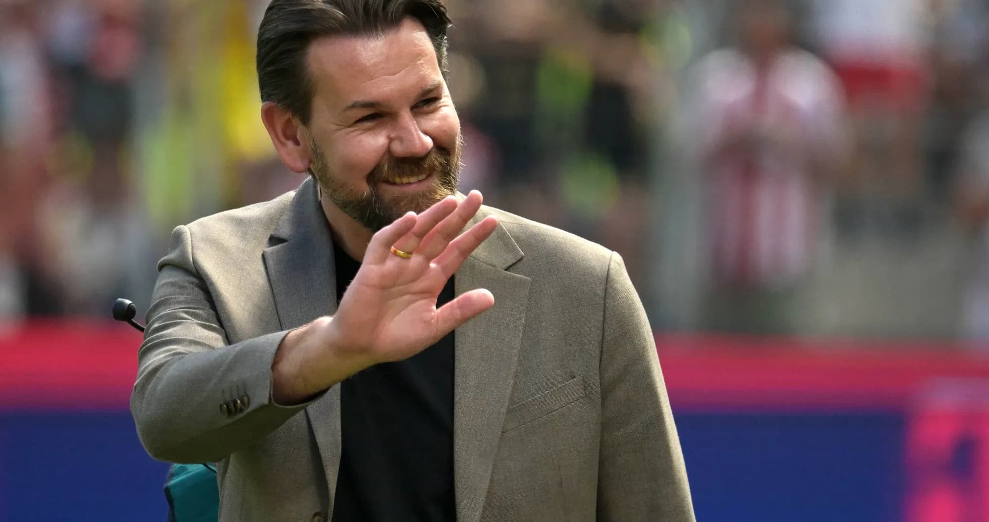 A man in a suit waving at the crowd