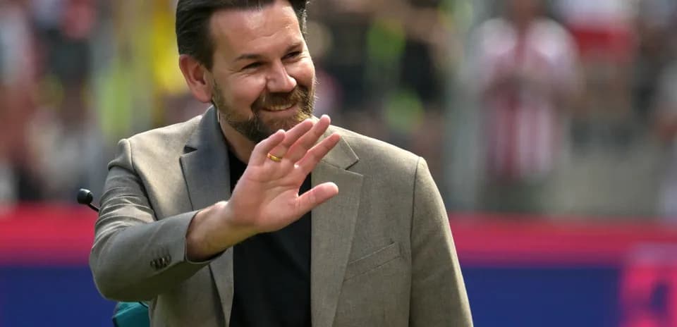 A man in a suit waving at the crowd