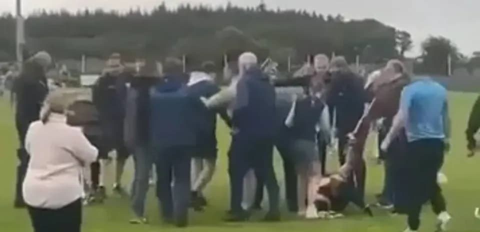 Crowd surrounding players on the field after match