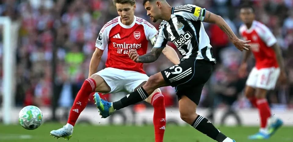 Newcastle player kicking ball while Arsenal player defends
