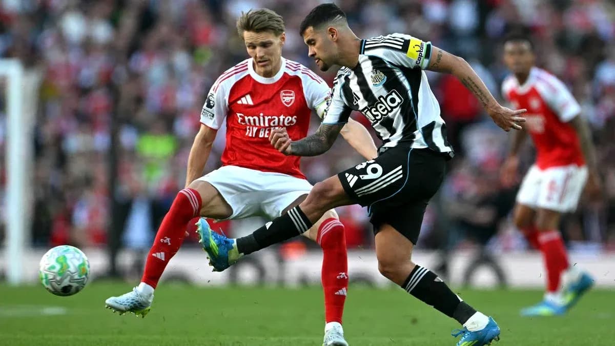 Newcastle player kicking ball while Arsenal player defends