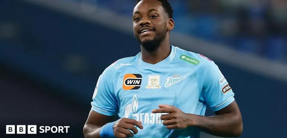 Futbolçu mavi forma ilə meydanda gülümsəyir