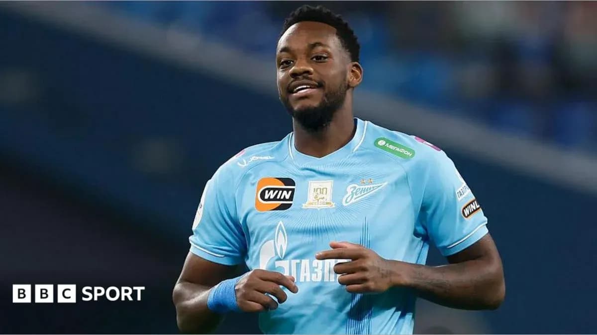 Futbolçu mavi forma ilə meydanda gülümsəyir