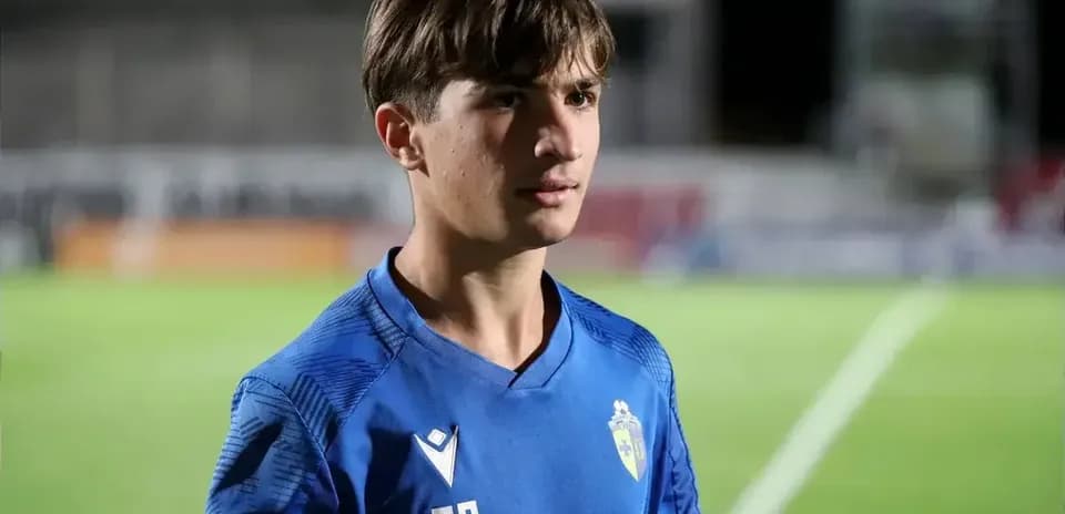 Gənc futbolçu mavi forma ilə meydanda durur