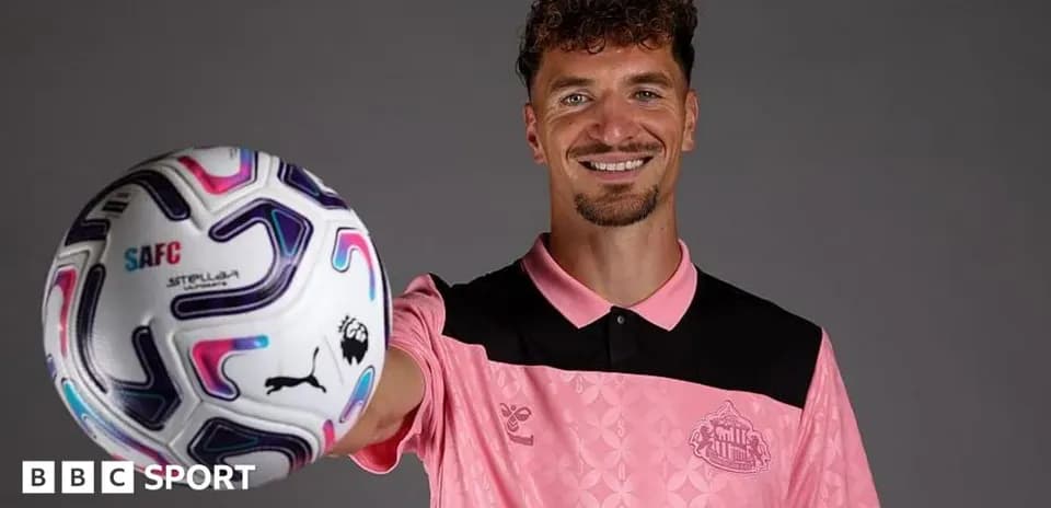 Futbolçu topu göstərərək gülümsəyir