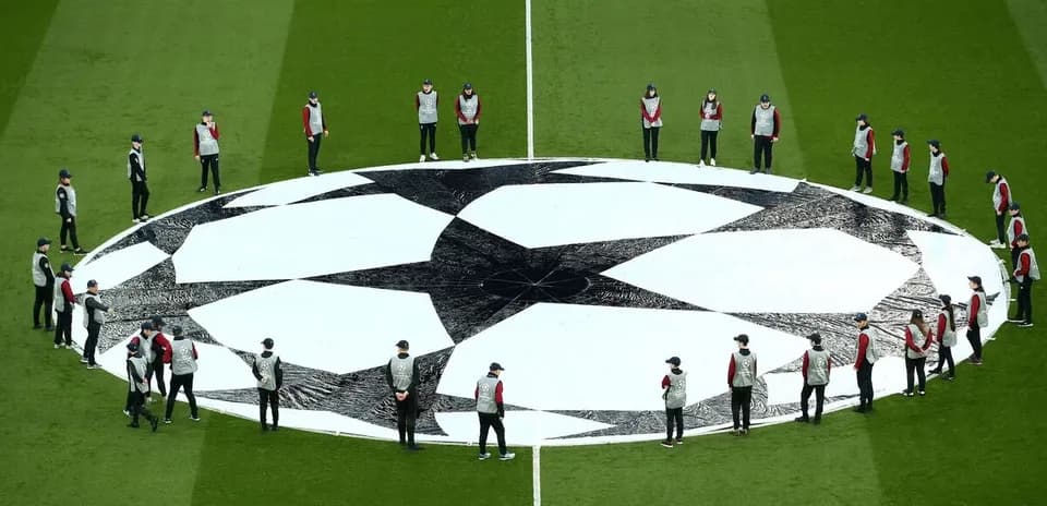 Staff arranging UEFA Champions League logo on field