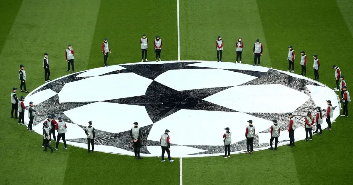Staff arranging UEFA Champions League logo on field