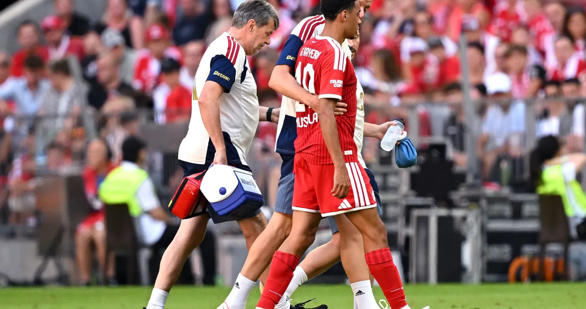 Player being assisted off the pitch by medical staff