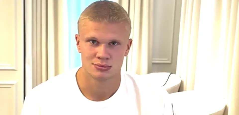 Young man sitting indoors, looking at camera