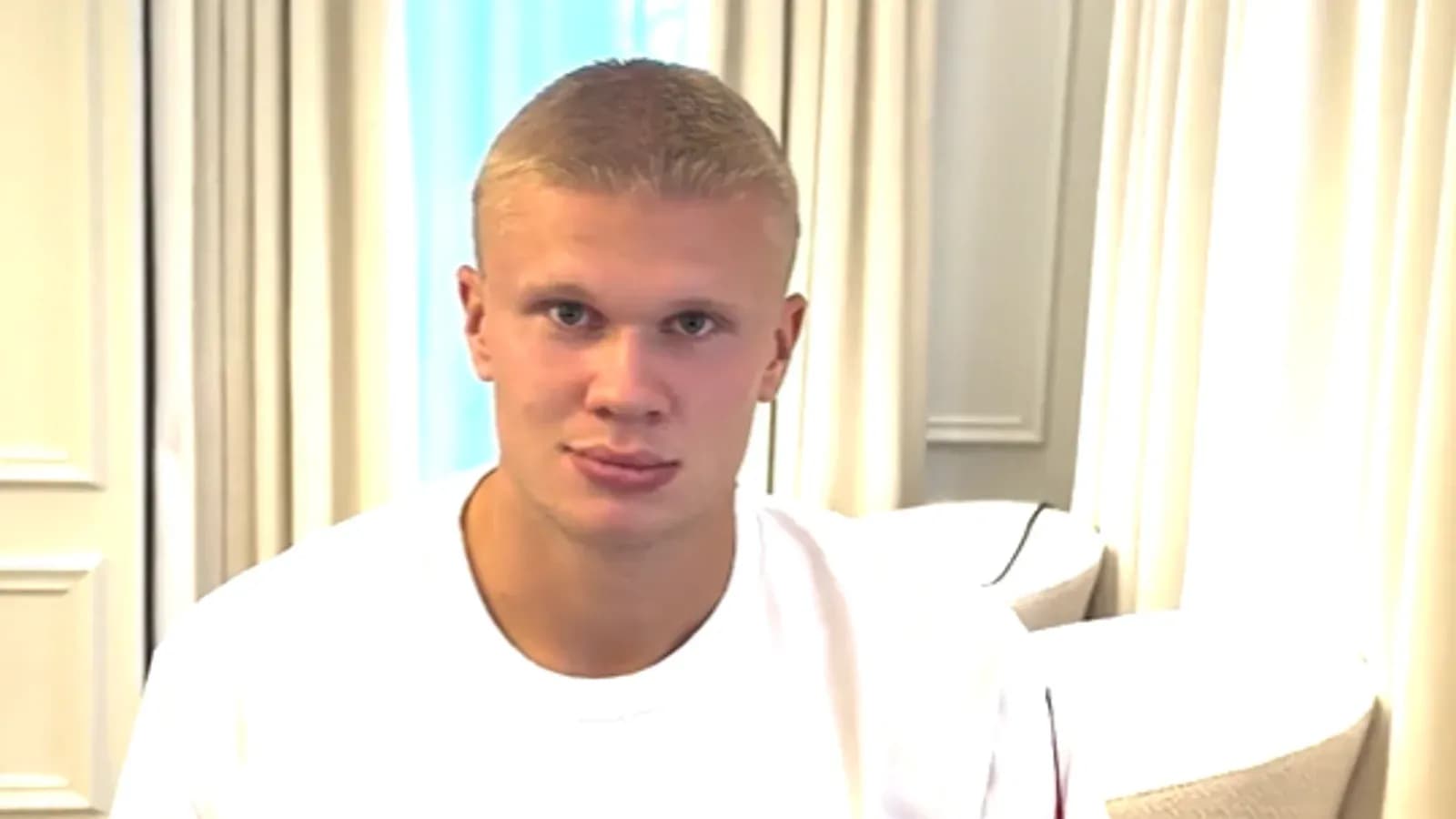 Young man sitting indoors, looking at camera