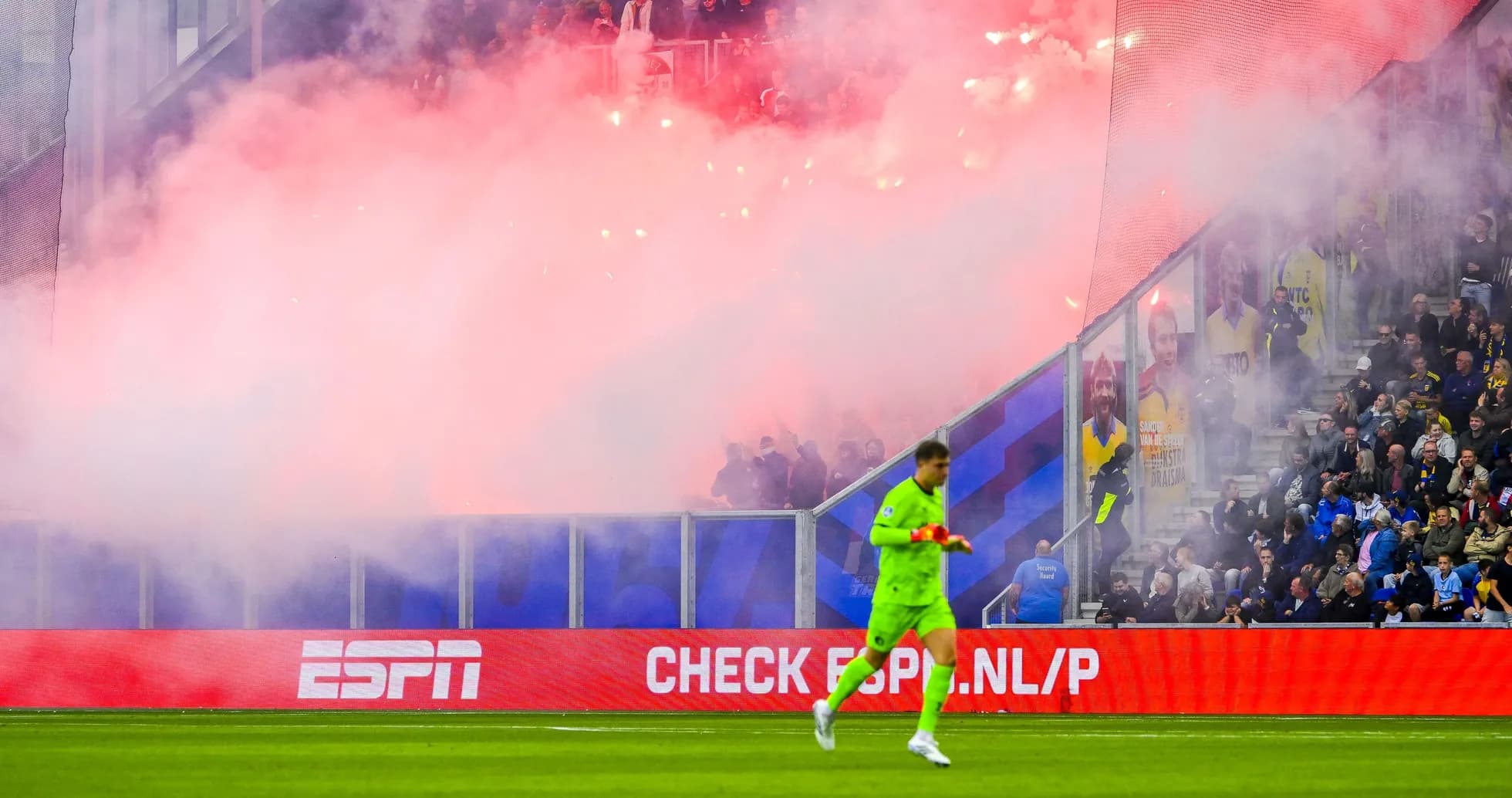 Goalkeeper walking past smoke from flares in stadium