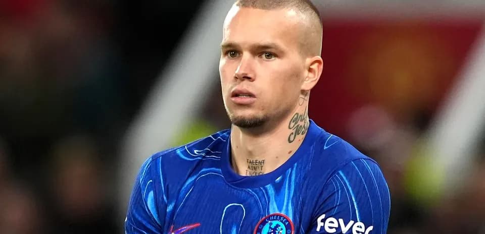 Futbolçu mavi forma ilə meydanda dayanıb