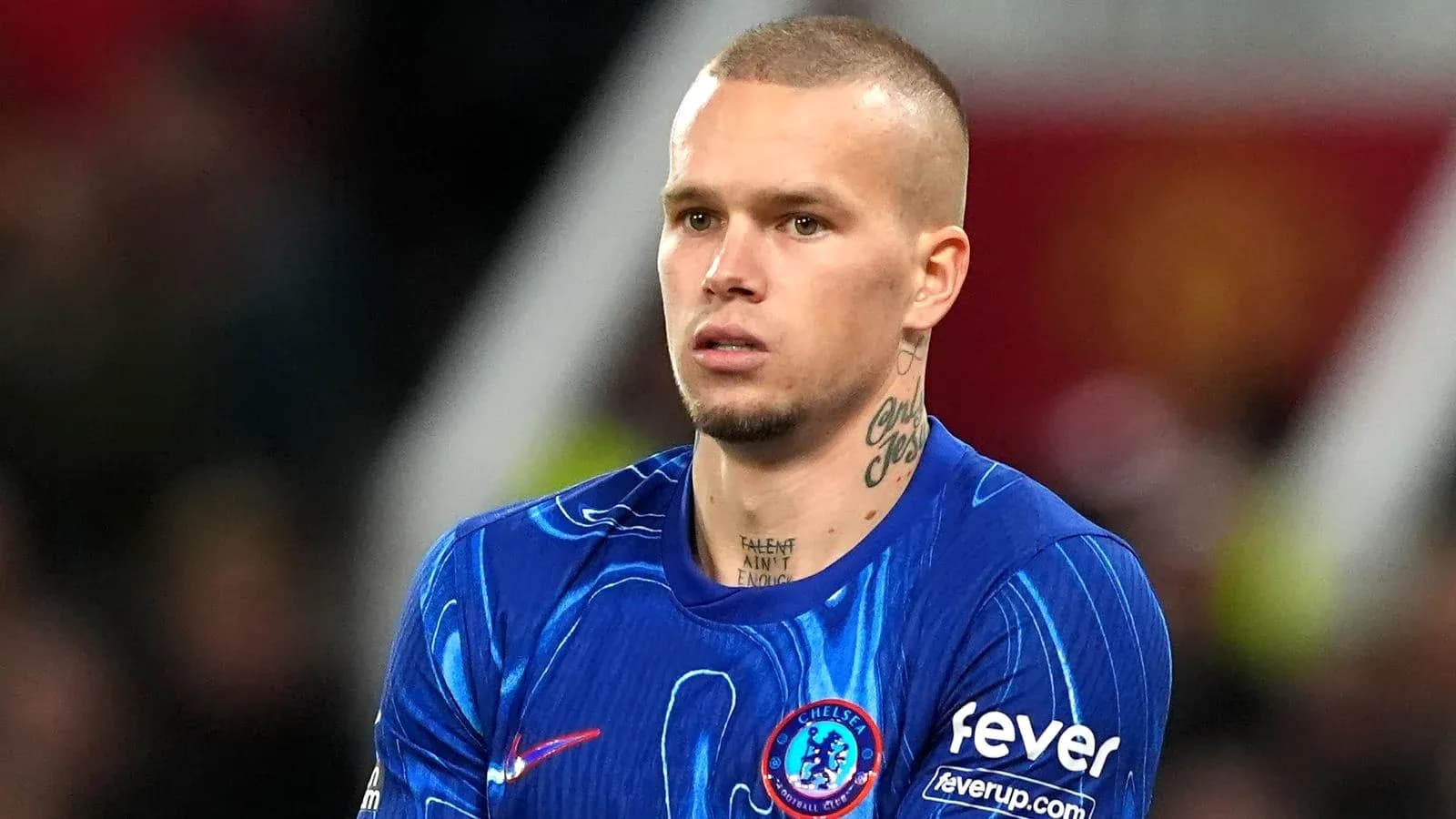 Futbolçu mavi forma ilə meydanda dayanıb