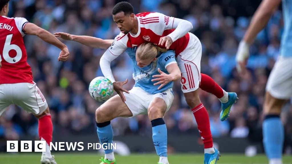 Arsenal player tackling Manchester City player during match