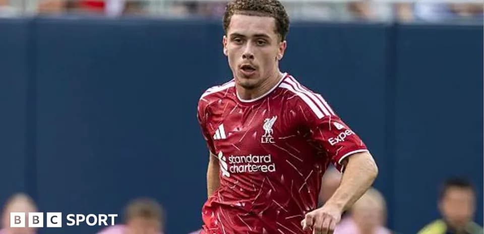 Futbolçu Liverpool formasında topa doğru irəliləyir