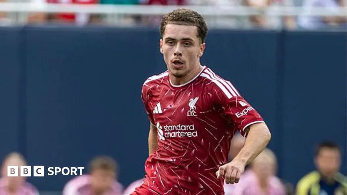 Futbolçu Liverpool formasında topa doğru irəliləyir