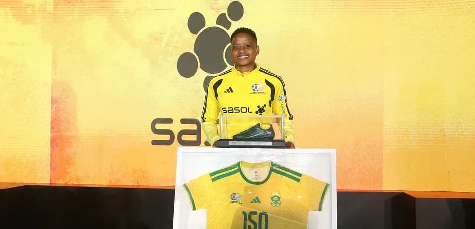 Player holding award with jersey and shoe display