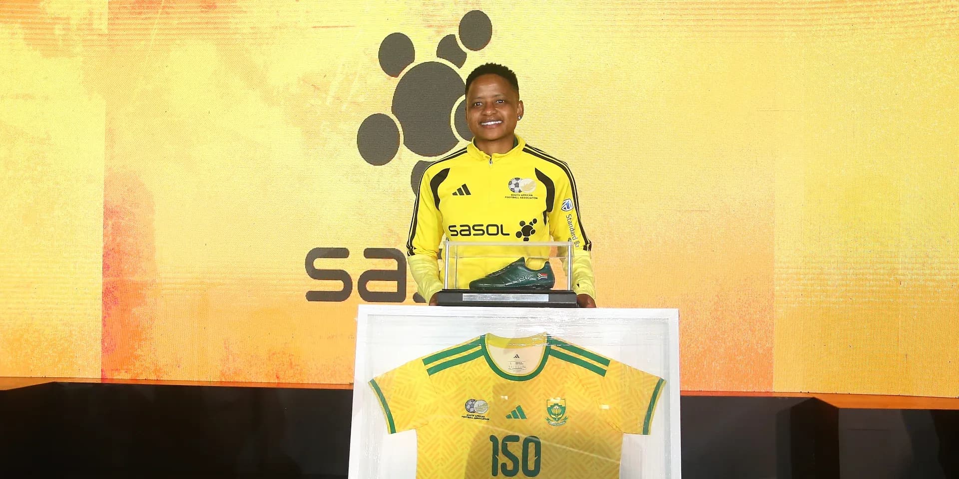 Player holding award with jersey and shoe display