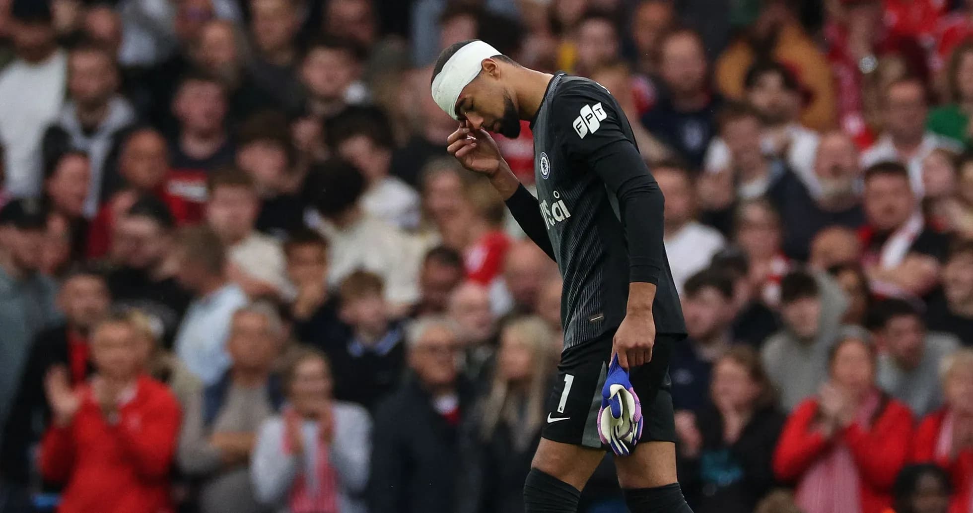 Goalkeeper with bandaged head walking past crowd