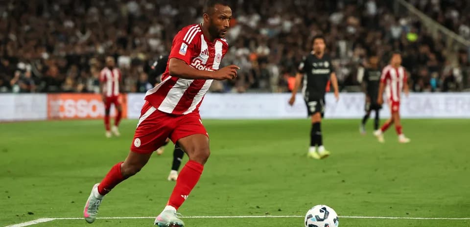 Futbolçu topa doğru qaçır, stadion arxa planda