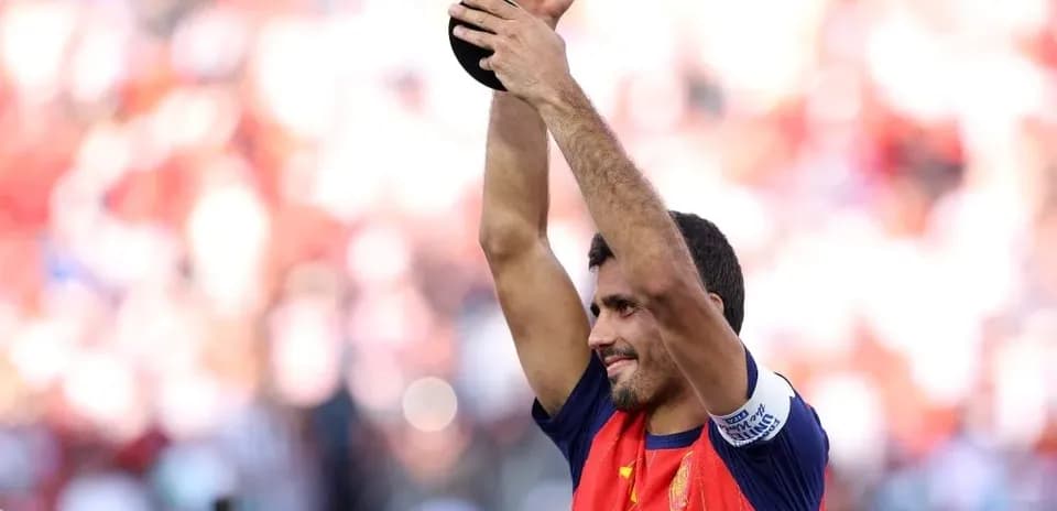 Futbolçu qızıl kuboku havada tutaraq sevinir