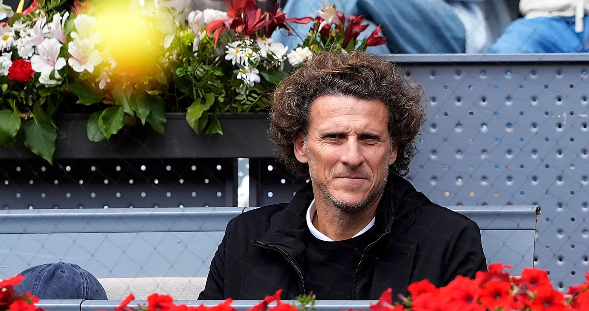 Spectator seated among flowers at tennis event