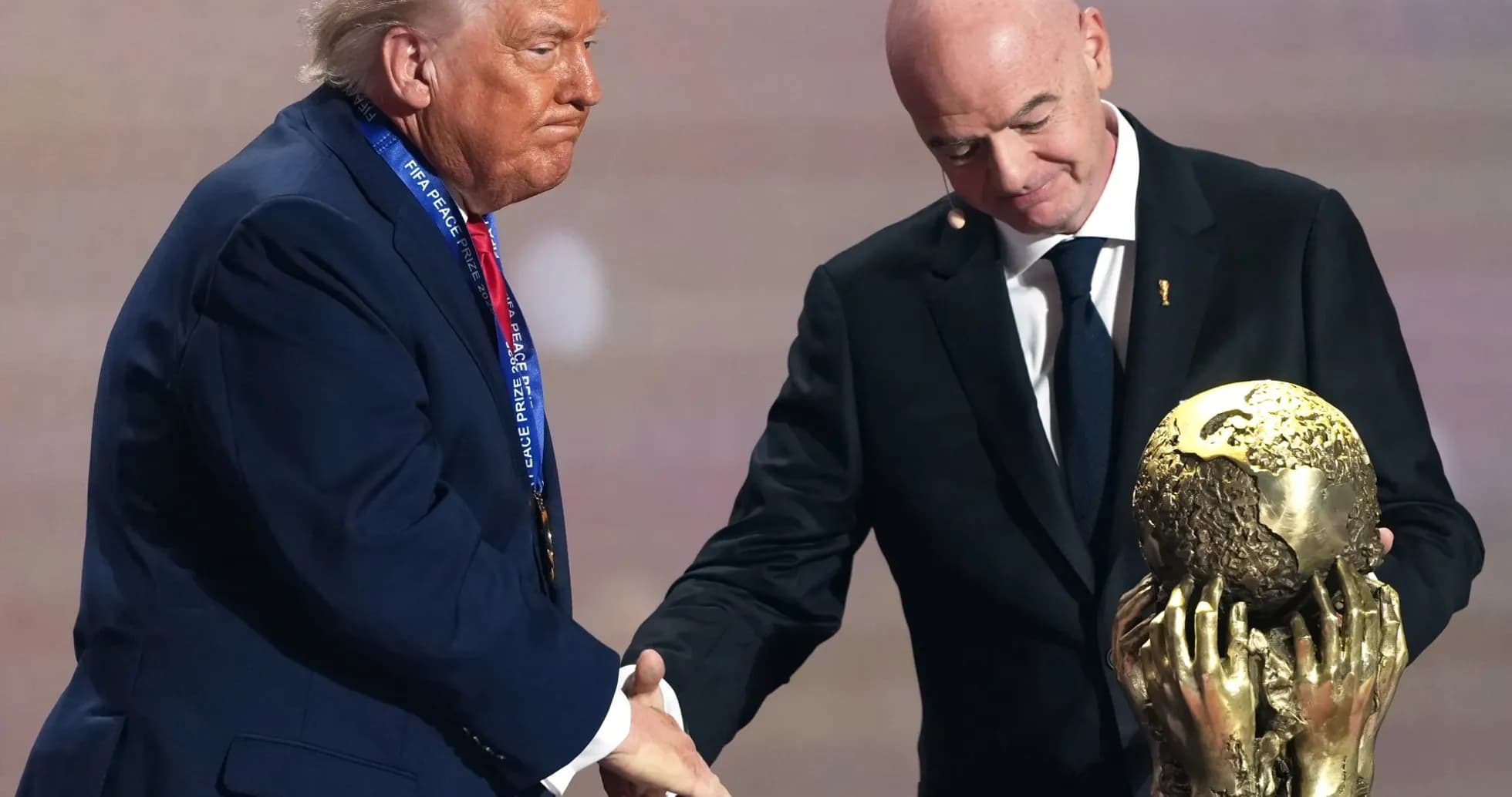 Two men shaking hands with FIFA Peace Prize trophy