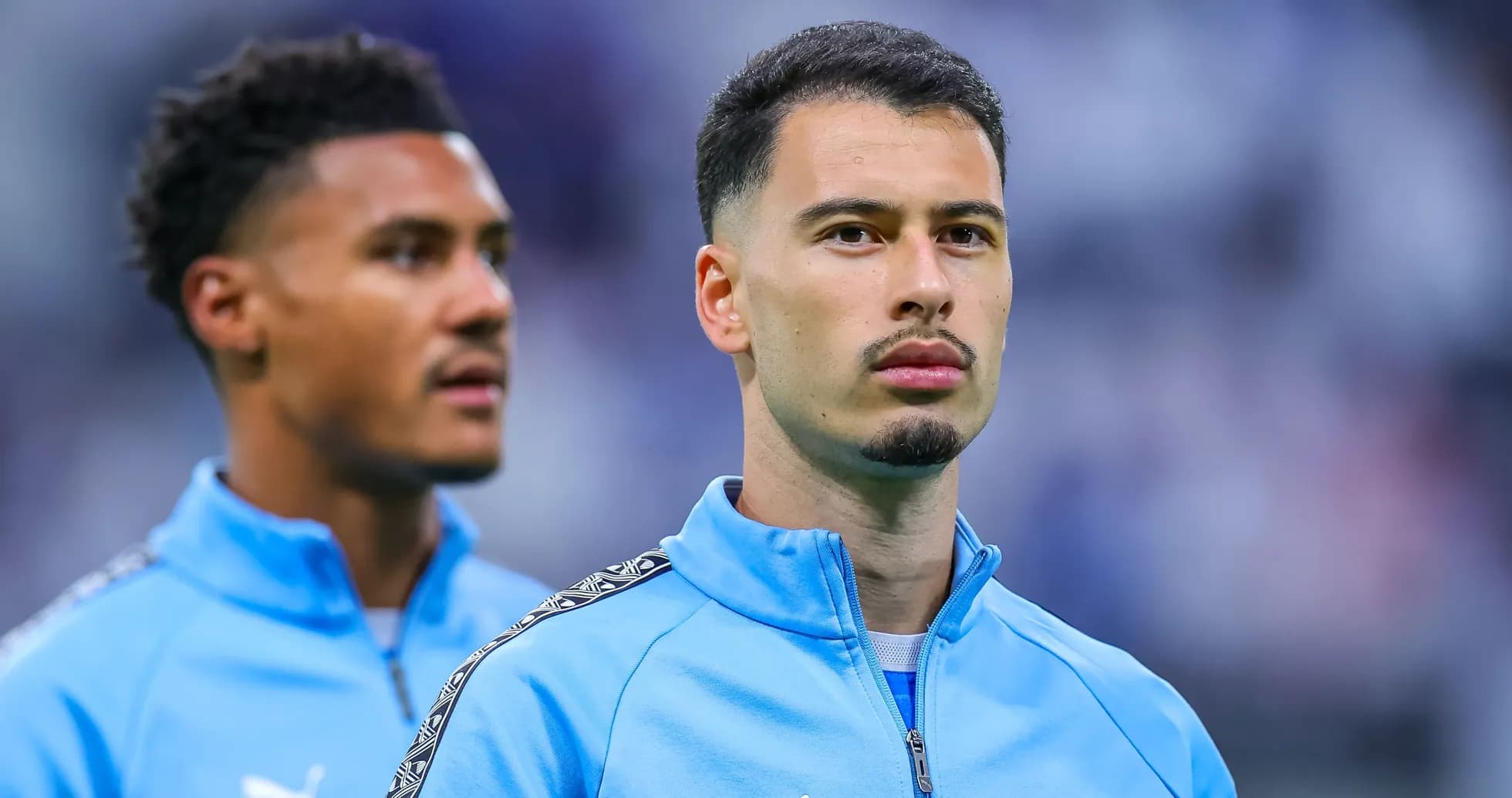 İki futbolçu mavi idman geyimində durur