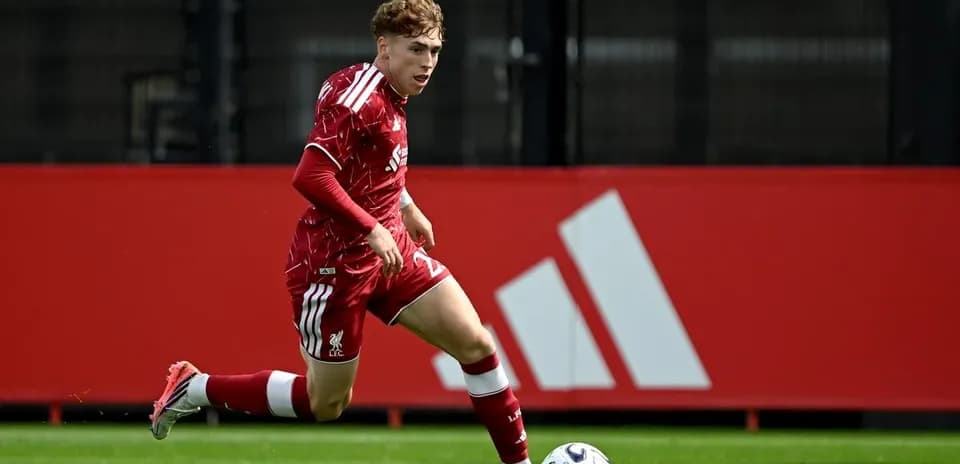 Oyunçu topu sürərək irəliləyir, Liverpool forması geyinib