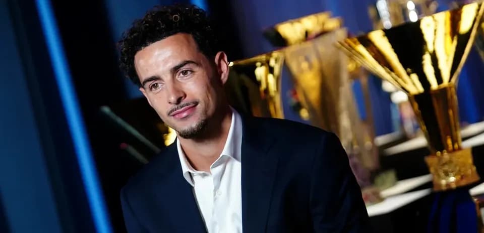 Young man in suit with trophies in background