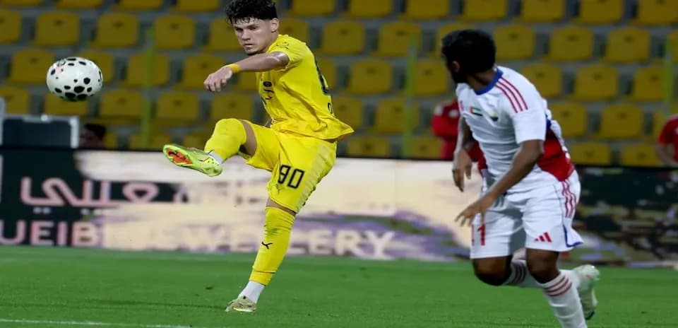 Oyun zamanı topa zərbə vuran futbolçu
