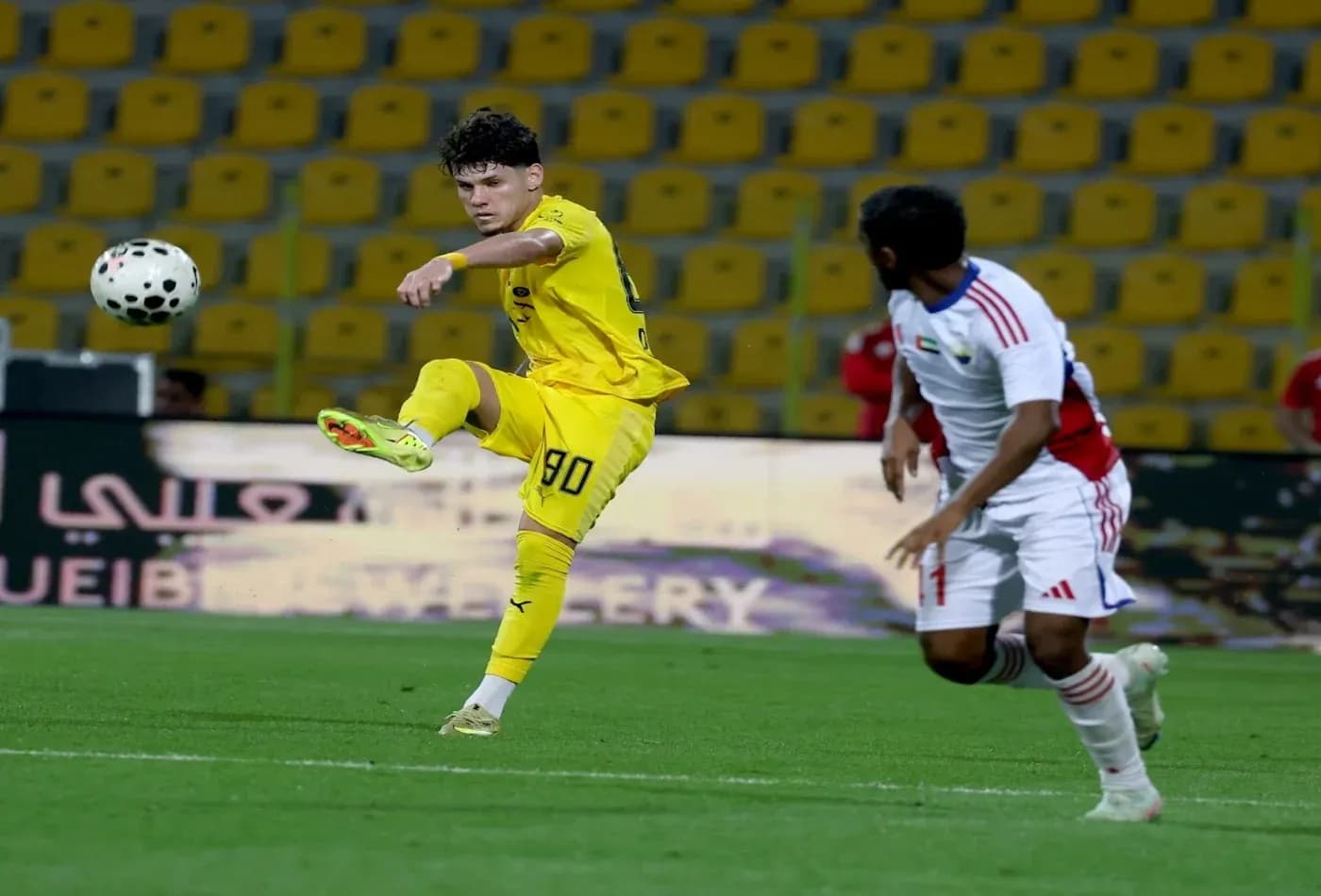 Oyun zamanı topa zərbə vuran futbolçu