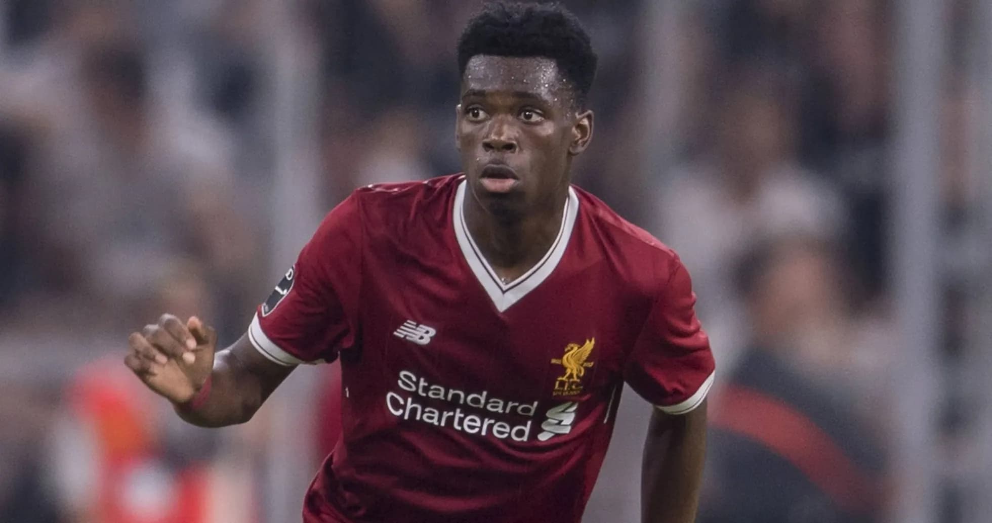 Futbolçu Liverpool formasında topa doğru irəliləyir