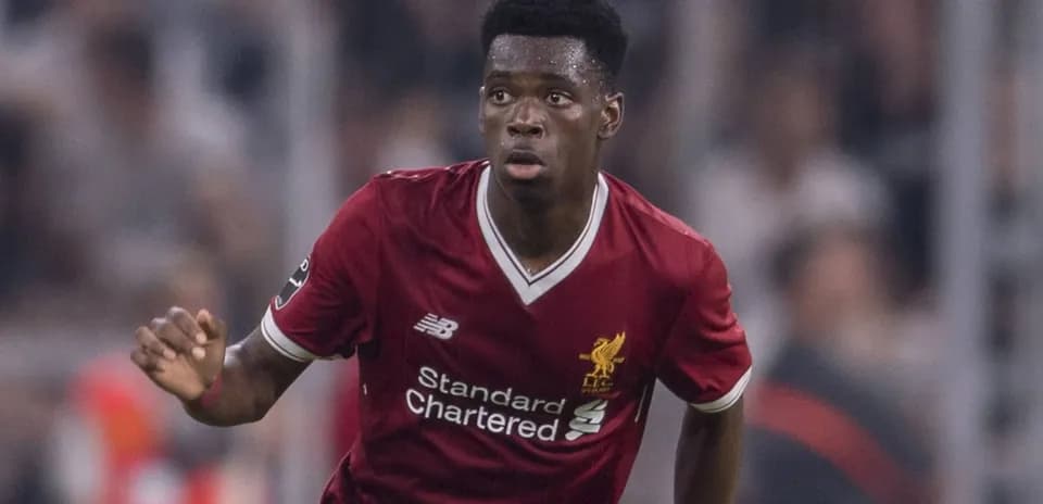 Futbolçu Liverpool formasında topa doğru irəliləyir