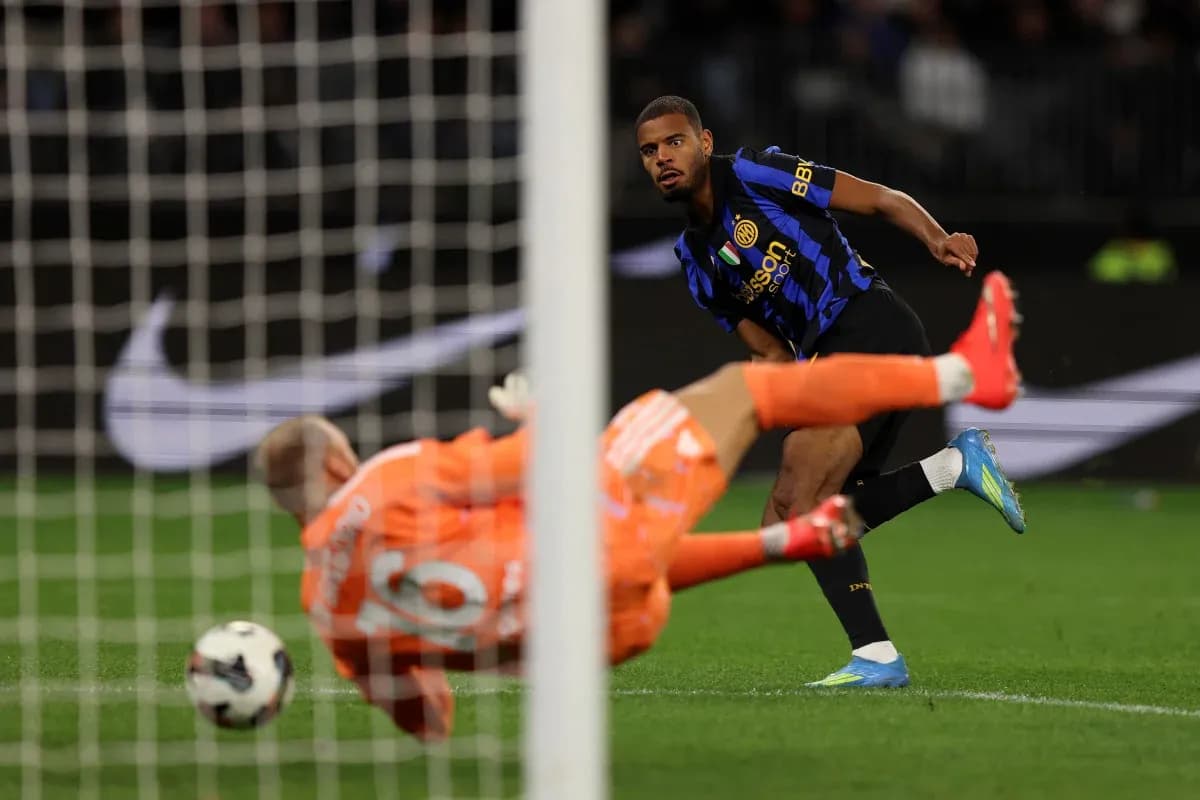 Player kicking ball past goalkeeper in match