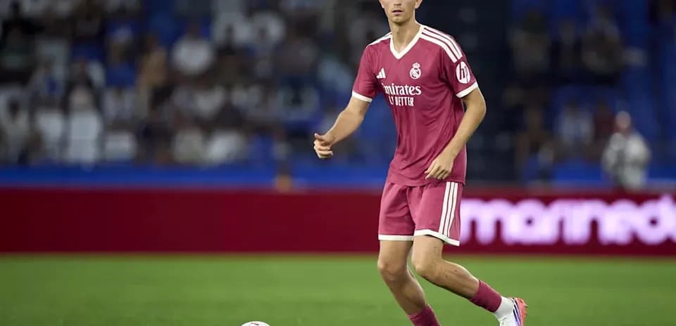 Futbolçu topa doğru yönelir, arka planda azarkeşlər