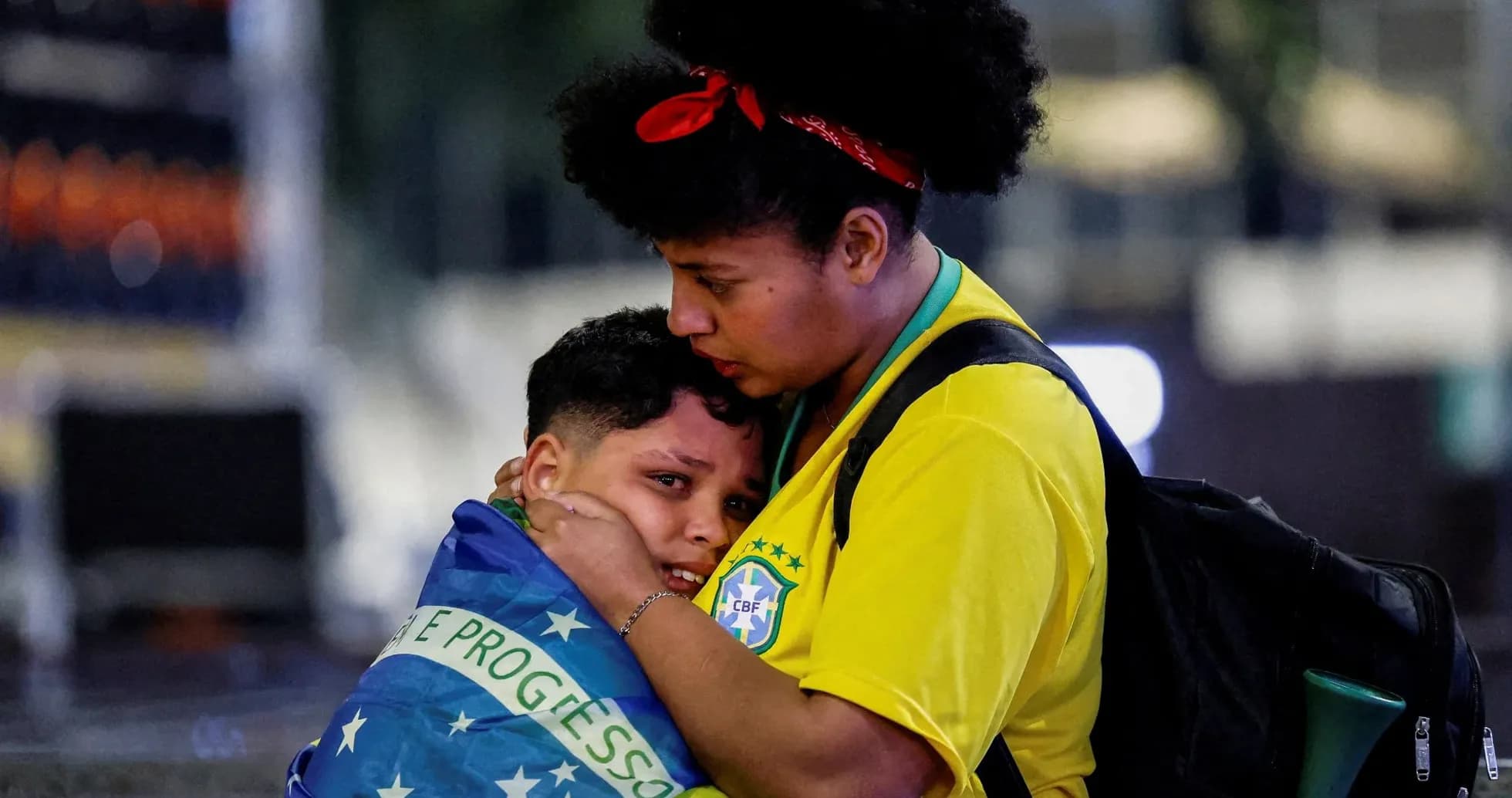 Fan comforting child wrapped in Brazilian flag