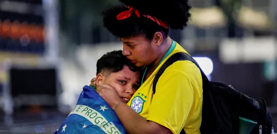 Fan comforting child wrapped in Brazilian flag