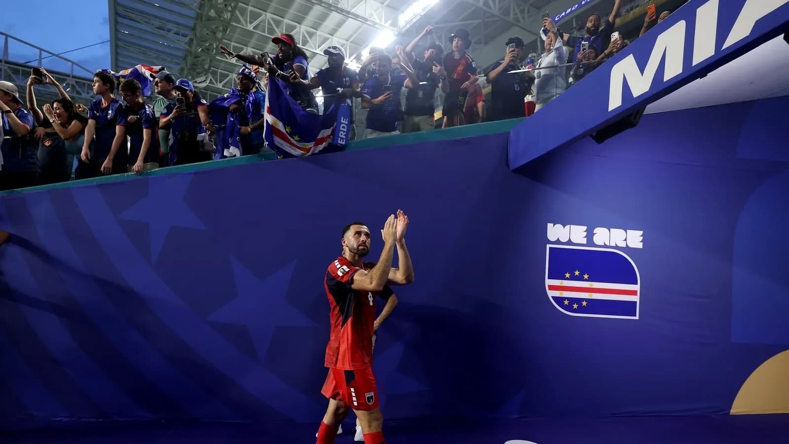 Futbolçu azarkeşlərə əl çırpır, Cape Verde bayrağı görünür