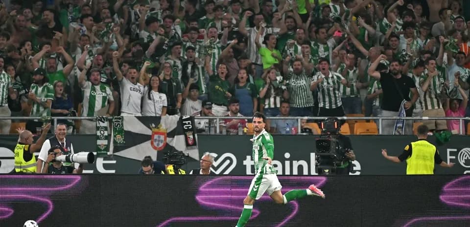 Futbolçu qolu qeyd edir, arxa planda azarkeşlər