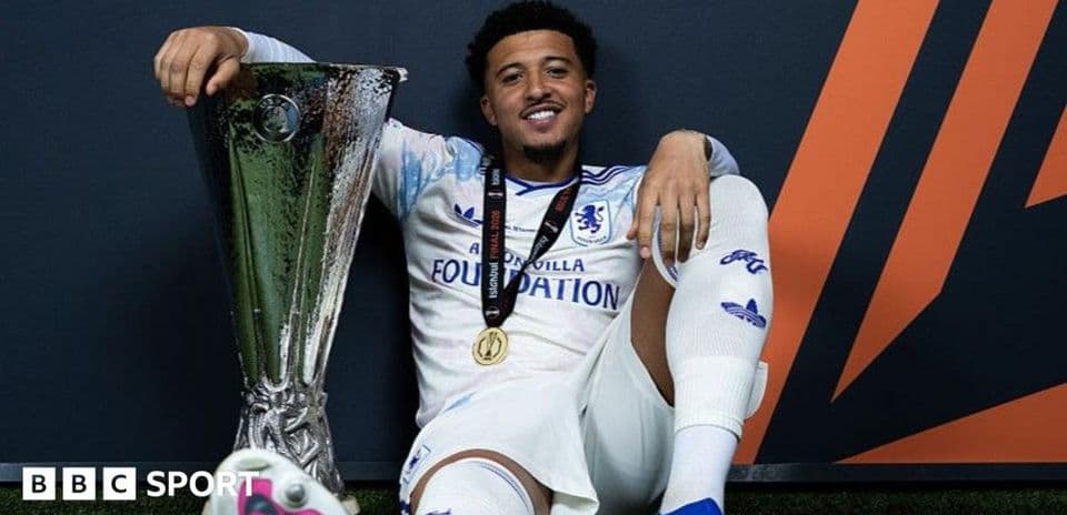 Futbolçu UEFA kubokunu tutaraq oturub
