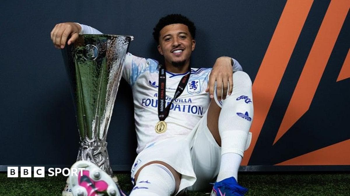 Futbolçu UEFA kubokunu tutaraq oturub